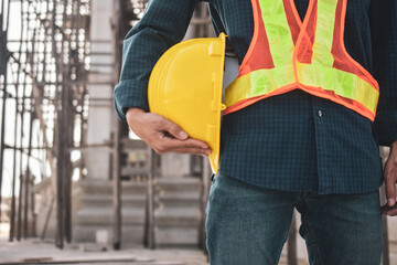 Close worker holding hard hat on site construction background