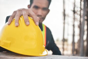 Close worker holding hard hat on site construction background