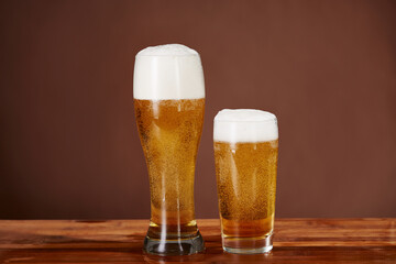 Cold beer with foam in a mug, on a wooden table and a dark background with blank space for a logo or text