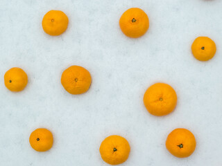 Bright ripe tangerines scattered in the fresh snow.