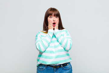 overweight woman feeling shocked and scared, looking terrified with open mouth and hands on cheeks