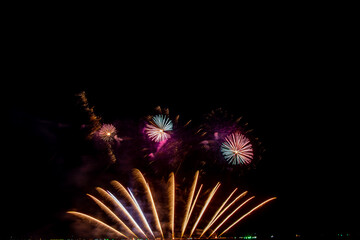 colorful fireworks,Beautiful multi color fireworks explosions lighting sky over trees silhouette and over an illuminated,celebration concept