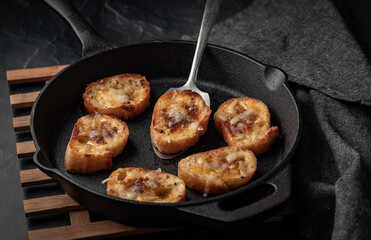 Cast iron fry pan filled with fried cheese bread rounds ready for serving.