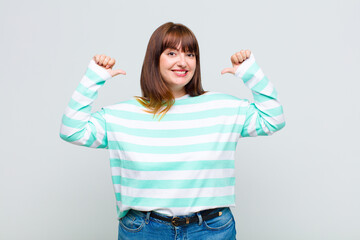 overweight woman feeling proud, arrogant and confident, looking satisfied and successful, pointing...