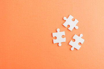 Fototapeta Top view flat lay of three paper plain white jigsaw puzzle game last pieces for solve, studio shot on an orange background, quiz calculation concept obraz