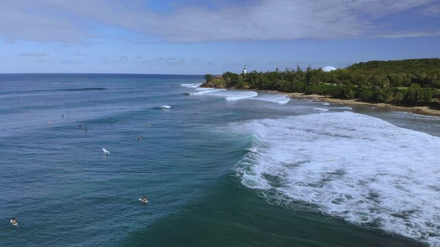 Waves near rincon Puerto Rico lighthouse with surfers floating in the ocean