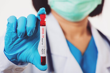 Doctor scientist in white uniform wear a mask holding test tube Coronavirus test blood sample in a...