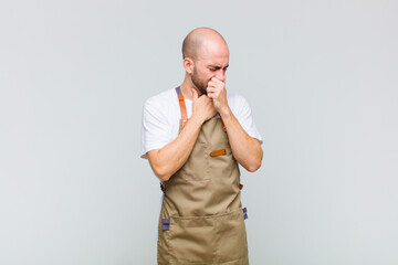 bald man feeling ill with a sore throat and flu symptoms, coughing with mouth covered