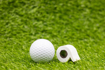 Naklejka premium Golf ball with toilet roll on green grass