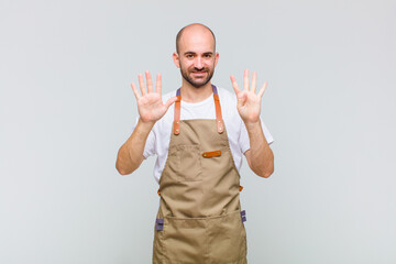 bald man smiling and looking friendly, showing number nine or ninth with hand forward, counting down