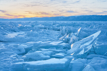 Fototapeta na wymiar Frozen Lake Baikal. Fields of ice hummocks in the Small Sea Strait at sunset on a cold evening. Winter landscape. Natural background