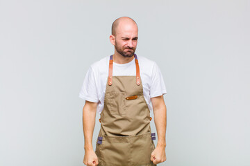bald man looking happy and friendly, smiling and winking an eye at you with a positive attitude