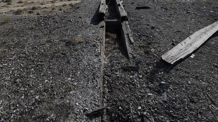 Tilt up over mountains in the desert with mine ore loading area built out of railroad ties