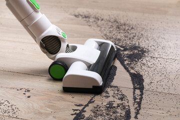 A man uses a bagless vertical cordless vacuum cleaner to clean the floor.