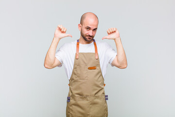 bald man feeling proud, arrogant and confident, looking satisfied and successful, pointing to self