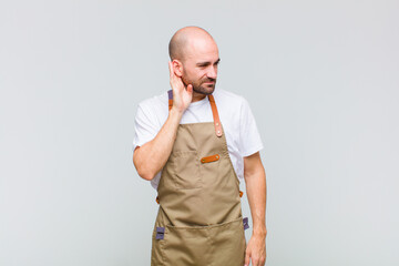 bald man looking serious and curious, listening, trying to hear a secret conversation or gossip,...