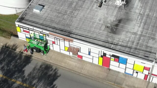 Drone shot of local artist painting mural on a scissor lift.