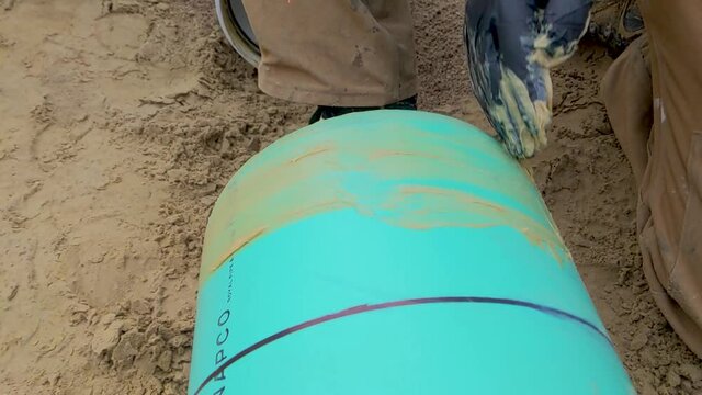 Construction worker spreading pipe lube / grease on the end of a sewer pipe in preparation for assembly. Installing underground SDR gravity sewer pipe. Slow Motion
