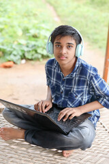 Fototapeta premium Portrait of Indian boy using laptop while attending the online classes at home outside