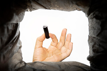 a man throws a battery is used into a trash can. Bottom view from the trash can. problem of...