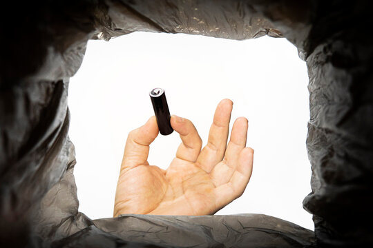 a man throws a battery is used into a trash can. Bottom view from the trash can. problem of recycling and pollution of the planet with garbage.