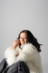  brunette young woman in faux fur jacket posing on white background