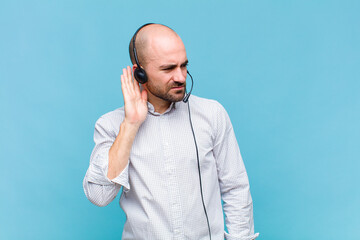 bald man looking serious and curious, listening, trying to hear a secret conversation or gossip,...
