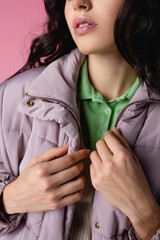 cropped view of woman in stylish puffer jacket on pink background