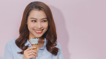 cute young woman smiling and eating ice cream on pink background