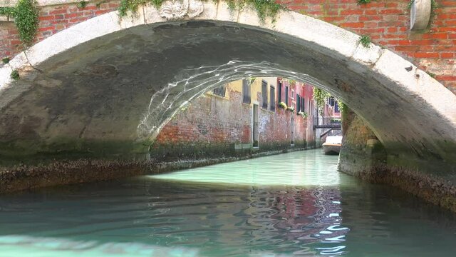Gondolas going in canals in Venice Italy. Gondola is a traditional, flat-bottomed Venetian rowing boat, well suited to the conditions of the Venetian lagoon. It is similar to a canoe. It is propelled 