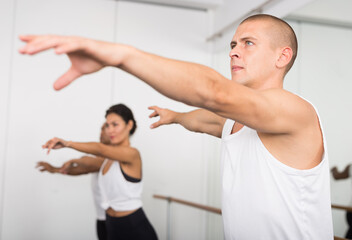 Group of multiethnic dancers training in bright fitness room