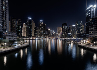 Dubai Marina Yacht Club long exposure vintage look at night with lights of skyline and creek for luxury vacation and travel