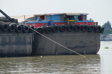 A tugboat unloads sandy cargo in the Chao Phraya River of Thailand