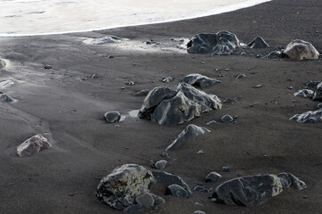 Black volcanic stones on black coastal sand