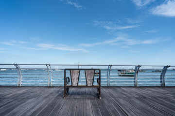 Fototapeta na wymiar Bench on the port deck under the blue sky