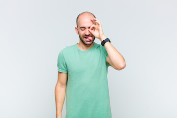 bald man smiling happily with funny face, joking and looking through peephole, spying on secrets