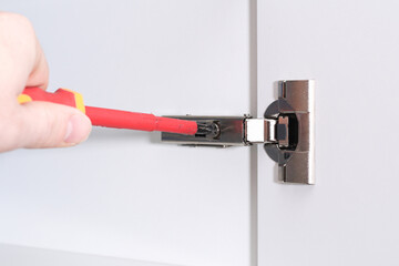 Man adjusts hinges soft closing on the cabinet door.