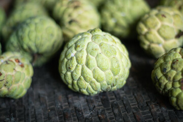 Obraz premium Selective focus of custard apple on old bamboo basket. Organic fruits from kitchen garden in Thailand.