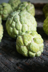 Selective focus of custard apple on old bamboo basket. Organic fruits from kitchen garden in Thailand.