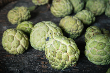 Selective focus of custard apple on old bamboo basket. Organic fruits from kitchen garden in Thailand.