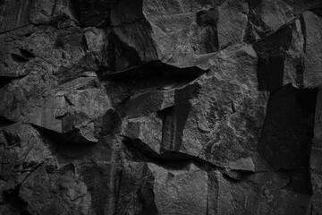 Black stone background. Rock texture. Fragment of the mountain surface. Close-up. Volumetric stone grunge background.