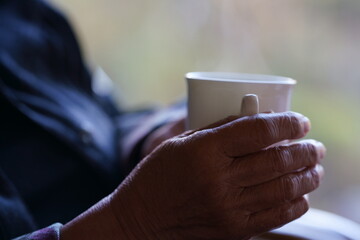 コーヒーカップを持つ高齢者の手元
