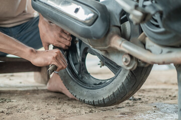 close up the tire repairman hand holding the tire pry tool when removing the motorbike tire in the...