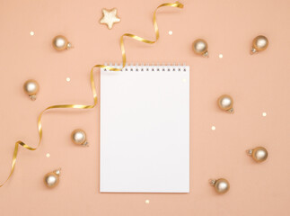 Christmas and new year card, or mock up on a pink peach background. Empty blank Notepad and small Golden balls, space for text.
