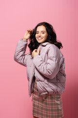  brunette young woman in puffer jacket posing on pink background