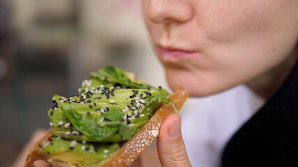 Diverse Mediterranean cuisine for health benefits. Vegan woman bites veggie rich toast with avocado...