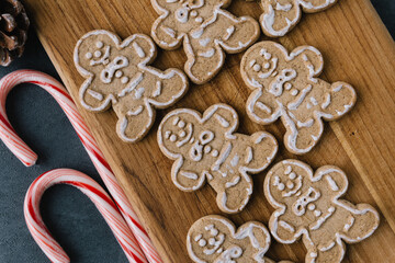 Christmas Gingerbread Man Cookies on Wooden Board With Candy Canes On Dark Slate Texture