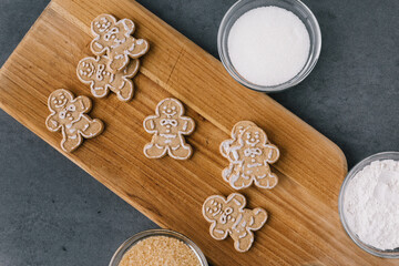 Christmas Gingerbread Man Cookies on Wooden Board With Sugar On Dark Slate Texture