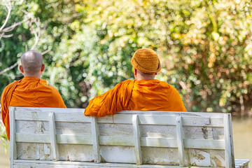 Monks sit on the river in Thailand.