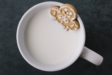 Christmas Holiday Gingerbread Man Cookie Sitting In Mug With Milk On Dark Slate Background